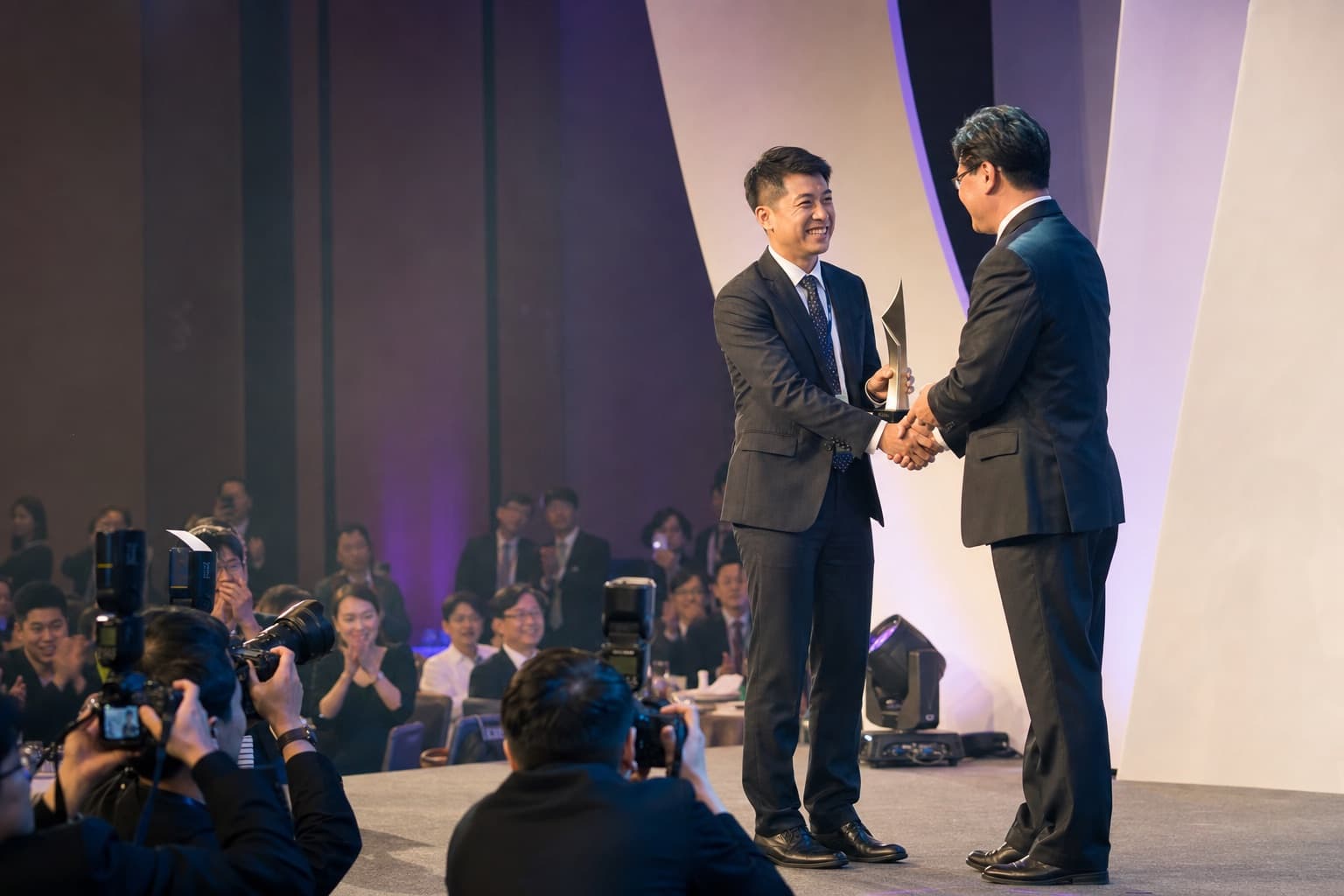 AI 生成的企業頒獎典禮攝影情境示意，得獎者在舞台接受獎座